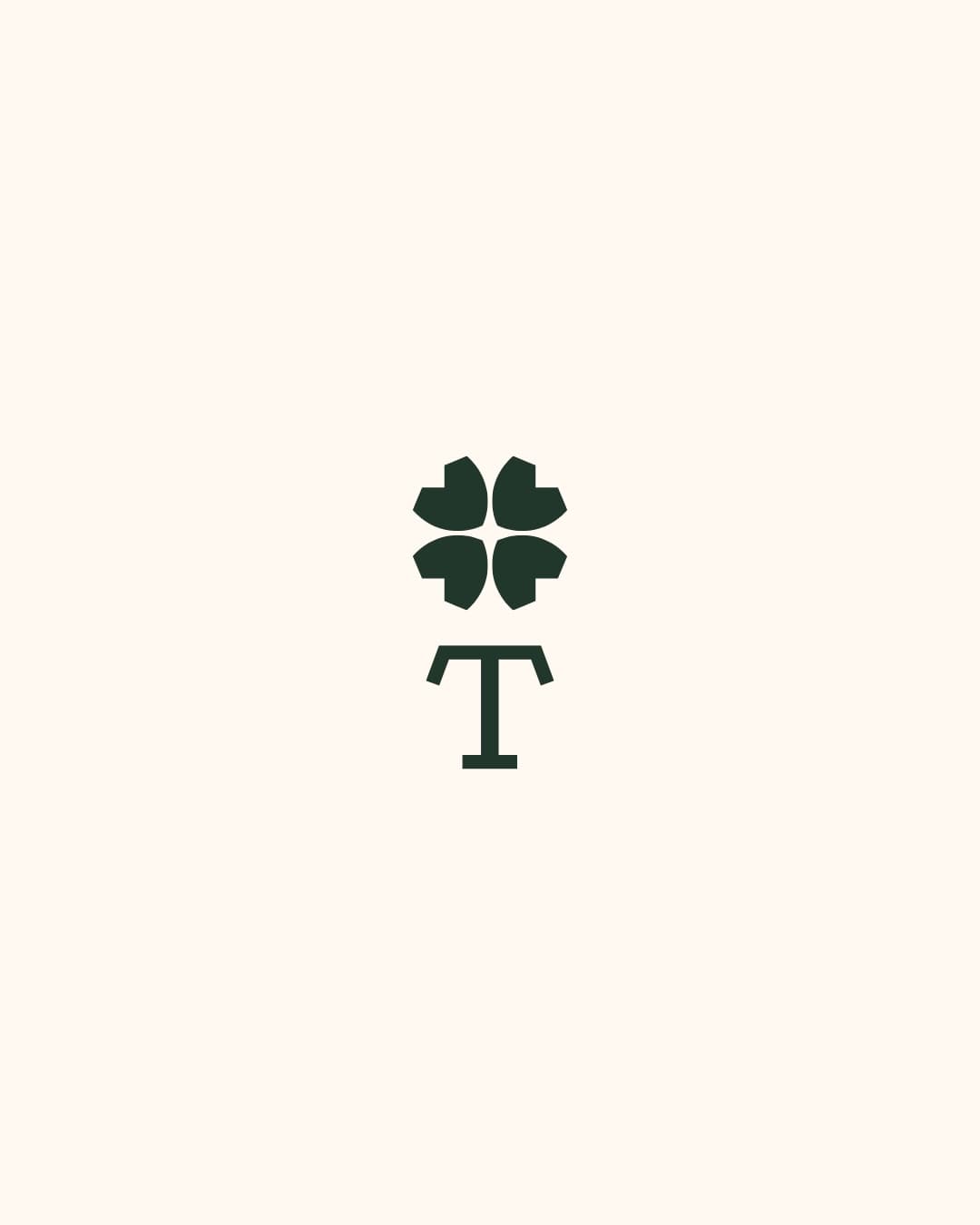 Symbole Treffel vert forêt sur fond ivoire : un trèfle stylisé au-dessus d’un T à empattements.