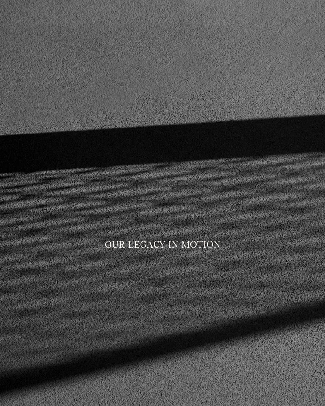 Photographie en noir et blanc d’ombres portées sur une surface texturée, avec l’inscription « Our legacy in motion ».